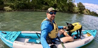 The Inflatable Kayak With A Feature That Makes Flatwater A Breeze Man and dog in inflatable kayak on river.