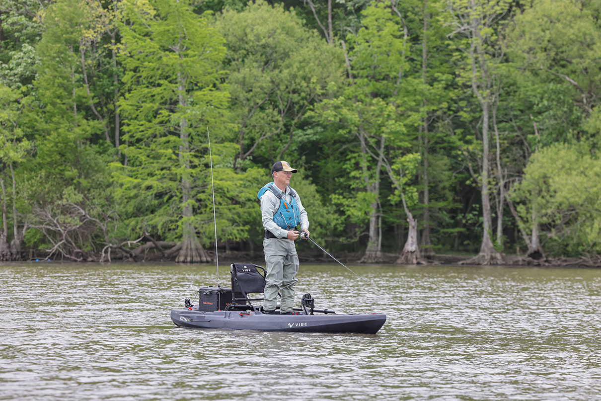 Man stands and casts from his fishing kayak