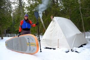 Paddleboarder with hot tent in winter