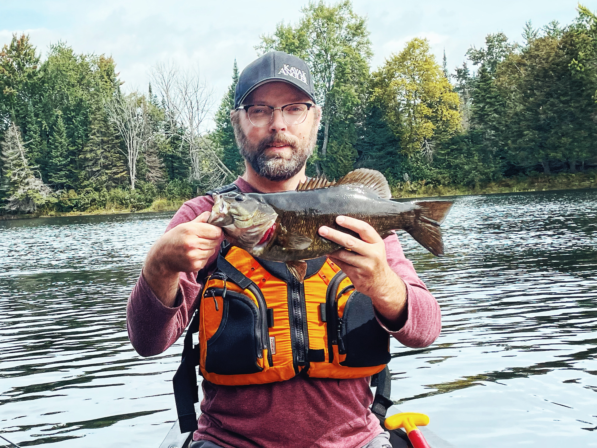 Man wearing fishing vest holds fish