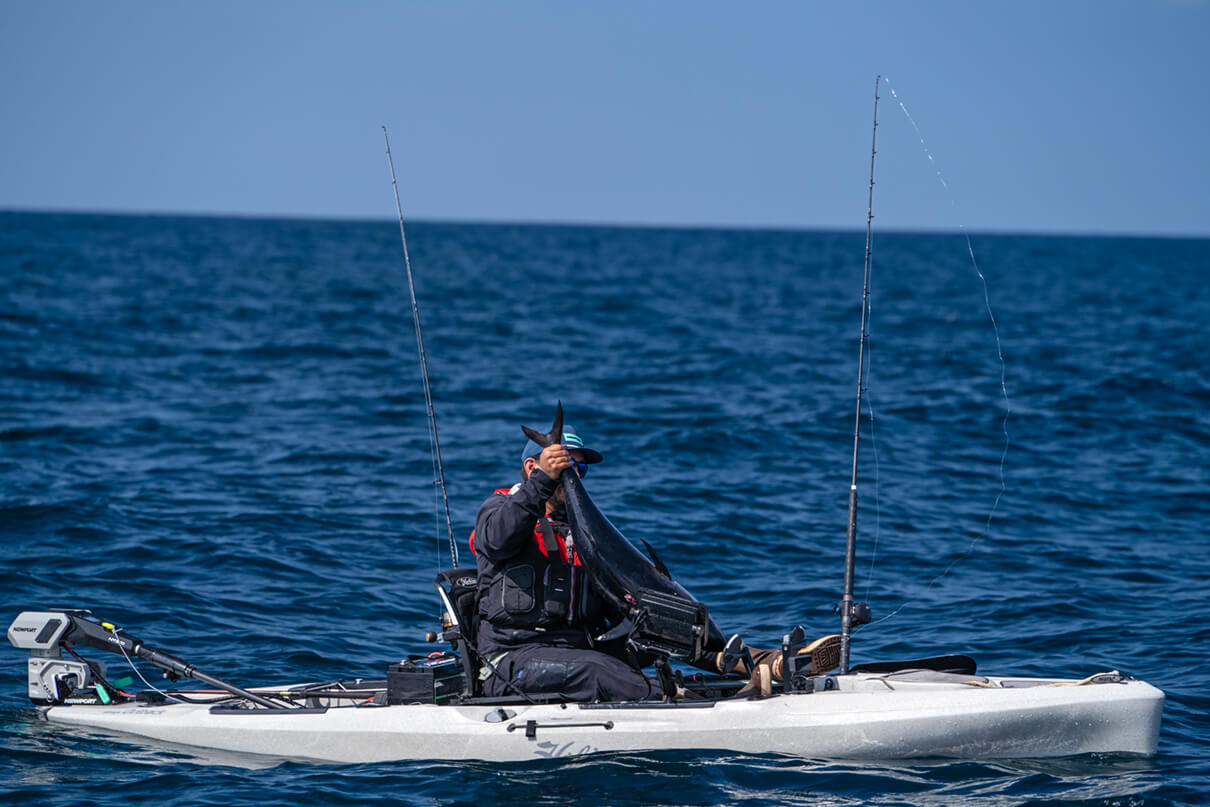 Howie Strech holding bluefin tuna by the tail on his kayak deck