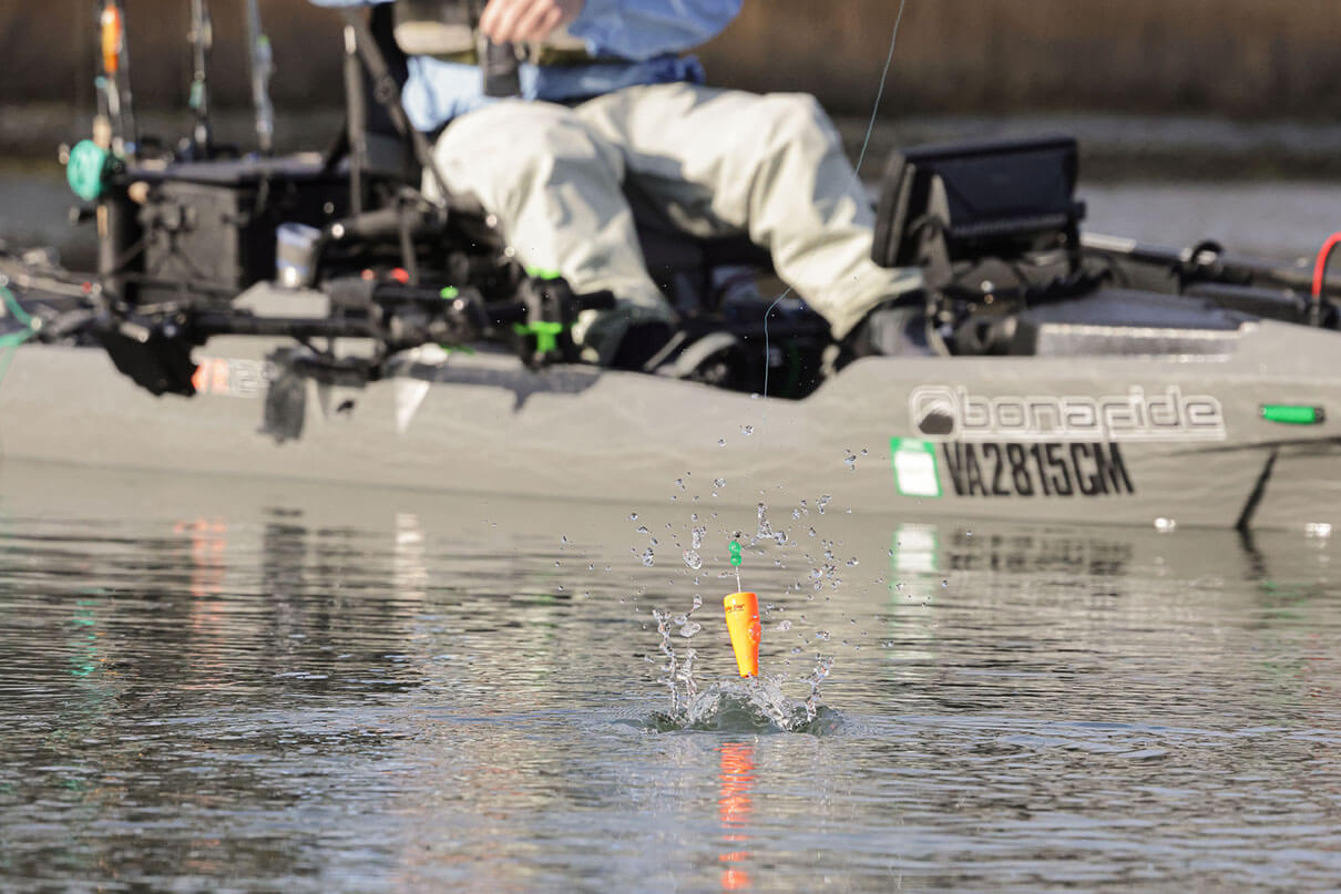 kayak angler casts a popping cork and it hits the water