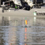 kayak angler casts a popping cork and it hits the water