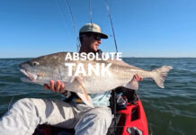 Image of Ethan Sommer holding a massive redfish in a fishing kayak