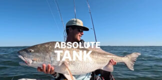 Image of Ethan Sommer holding a massive redfish in a fishing kayak
