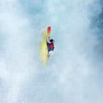 whitewater kayaker moves straight down in the midst of waterfall spray