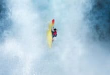 whitewater kayaker moves straight down in the midst of waterfall spray