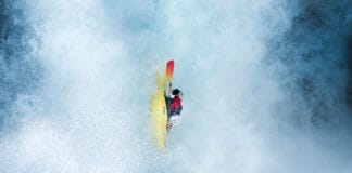 whitewater kayaker moves straight down in the midst of waterfall spray