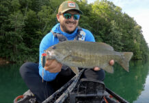 Best Smallmouth Bass Lures For 2025 Man holding smallmouth bass hooked with a large fishing lure.