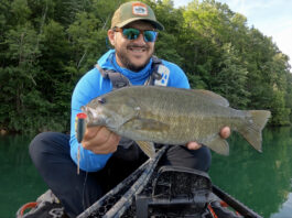 Man holding smallmouth bass hooked with a large fishing lure.