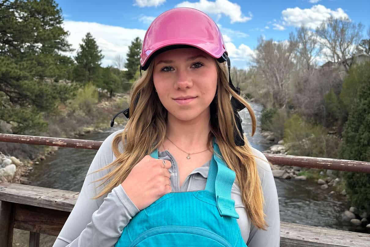 Makinley Kate Hargrove poses in paddling gear on a bridge above a river