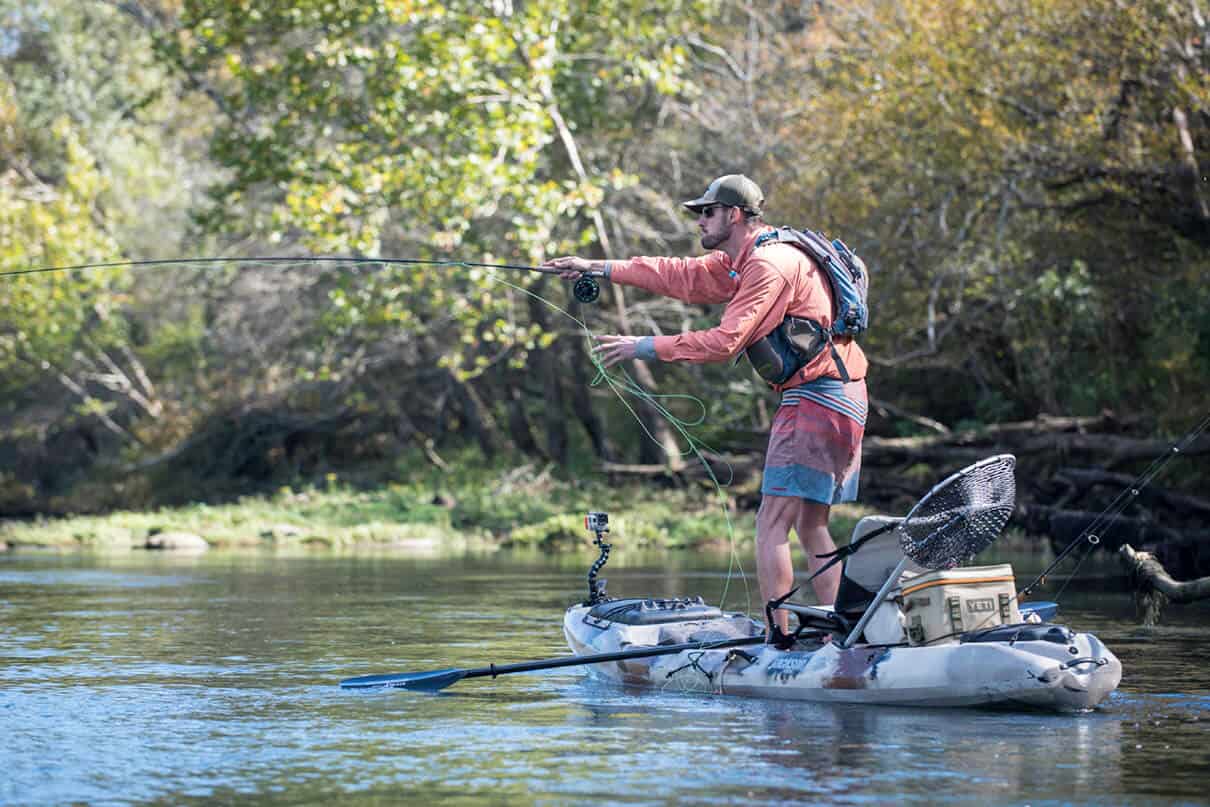 Man stands and fishes from a Jackson Kayak