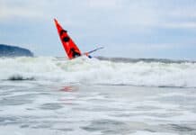 Deb Volturno On The Future of Sea Kayaking The bow of Deb Volturno's red kayak rising over the surf