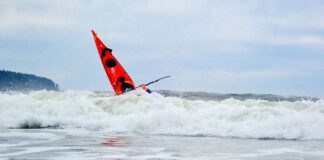 The bow of Deb Volturno's red kayak rising over the surf