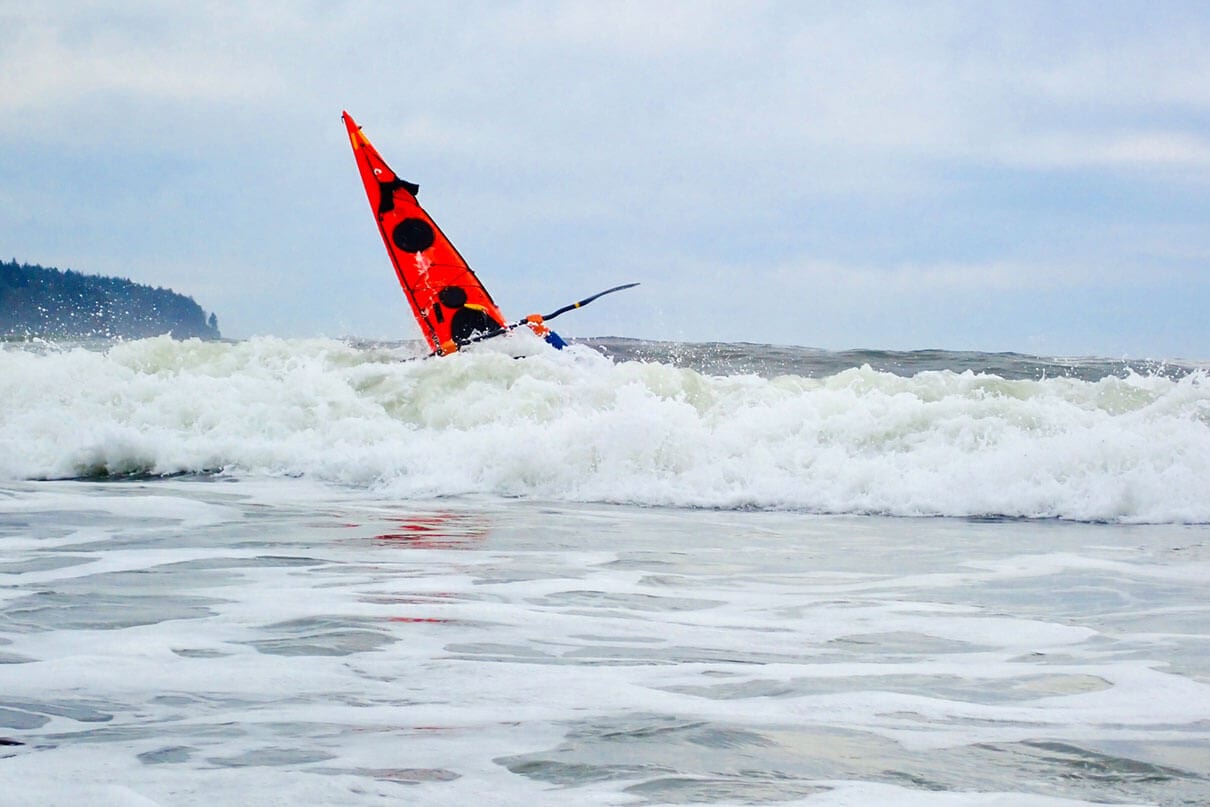 The bow of Deb Volturno's red kayak rising over the surf
