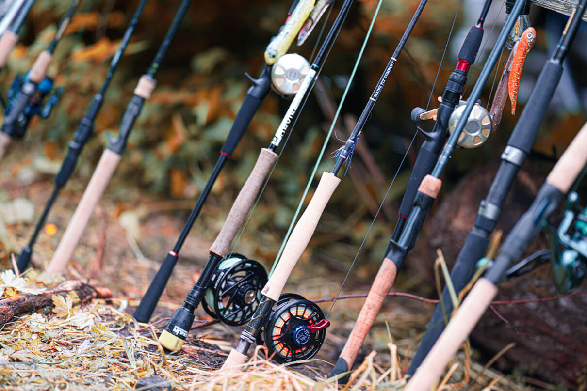 a bunch of fishing rods propped on the ground