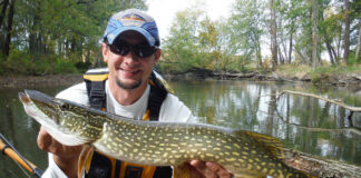 Kyle Hammond holds up a pike he caught while kayak fishing