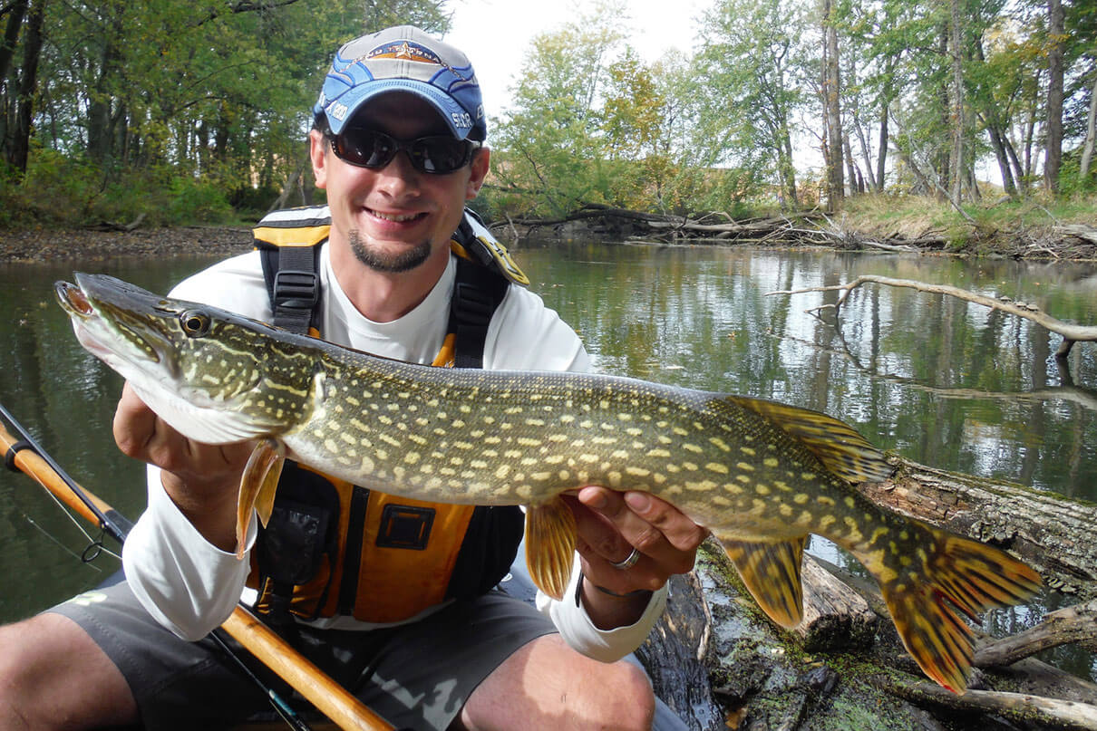 Kyle Hammond holds up a pike he caught while kayak fishing