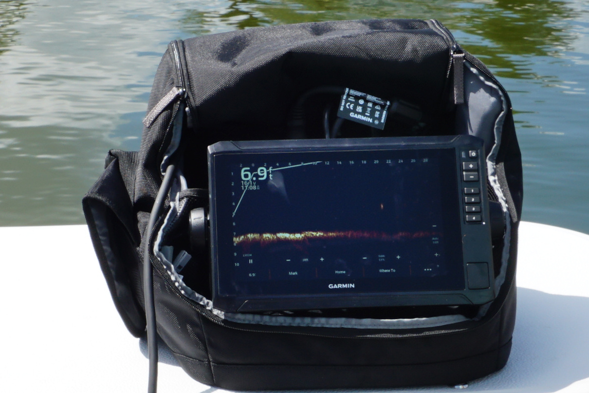 A Portable fish finder sitting in a bag on the deck of a boat.