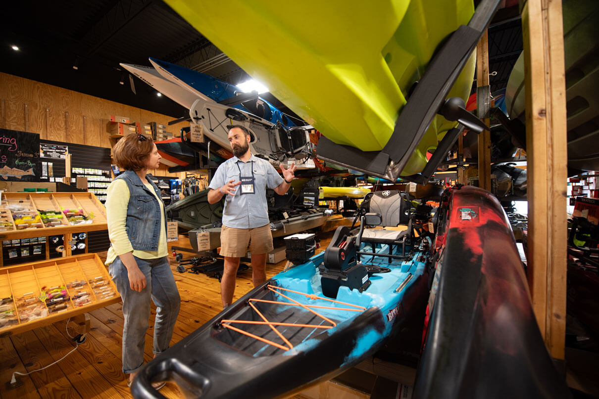 woman and employee talk about fishing equipment at a paddle shop