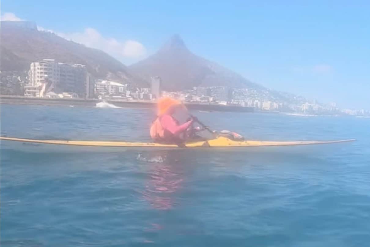 Image of a kayaker off the coast of Cape Town South Africa rescuing an endangered African Penguin