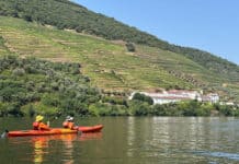 Join Our Upcoming Webinar On Kayak Expeditions In Portugal two people paddle an orange tandem kayak in front of terraced hills in the Douro river valley in Portugal