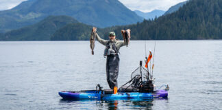 10 Expert Rigging Skills To Level Up Your Game man stands on a fully rigged fishing kayak and holds up two large saltwater fish he caught