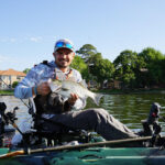 Learn How To Catch Hybrid Striped Bass kayak angler holds up a hybrid striped bass