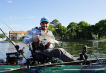 Learn How To Catch Hybrid Striped Bass kayak angler holds up a hybrid striped bass