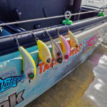 Wake Baits Go Saltwater Fishing a selection of wake baits are rigged to the side of a kayak before saltwater fishing