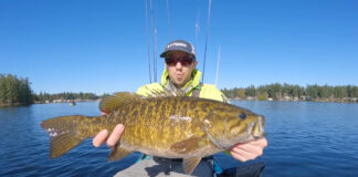 A kayak fisherman holds a massive bass up to the camera