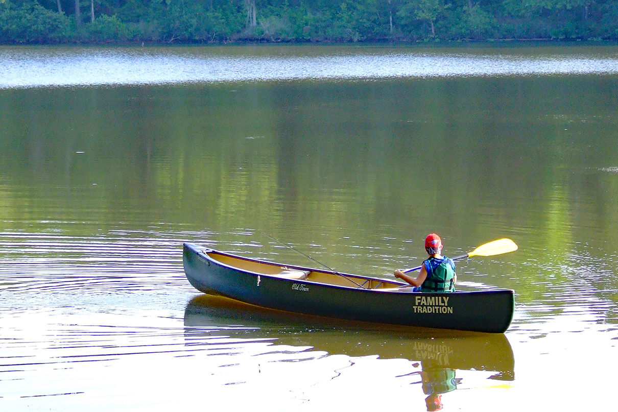 boy paddles a canoe on flatwater