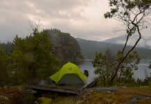 A Quick & Handy Guide to Repairing Waterproof Gear (Video) Image of a green tent with a rainfly on a tent platform in the rain