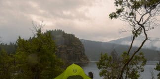 A Quick & Handy Guide to Repairing Waterproof Gear (Video) Image of a green tent with a rainfly on a tent platform in the rain