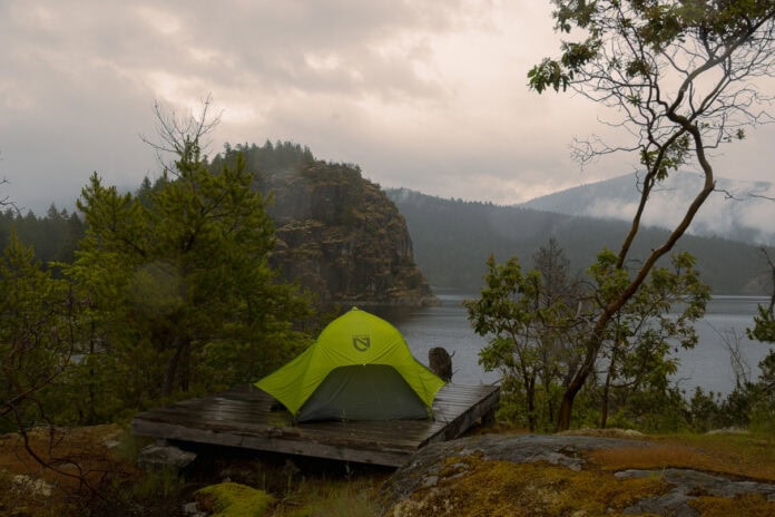 Image of a green tent with a rainfly on a tent platform in the rain