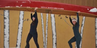 Best Base Layers For 2026 The author and Paddling Magazine editor-in-chief portaging a canoe wearing base layers.