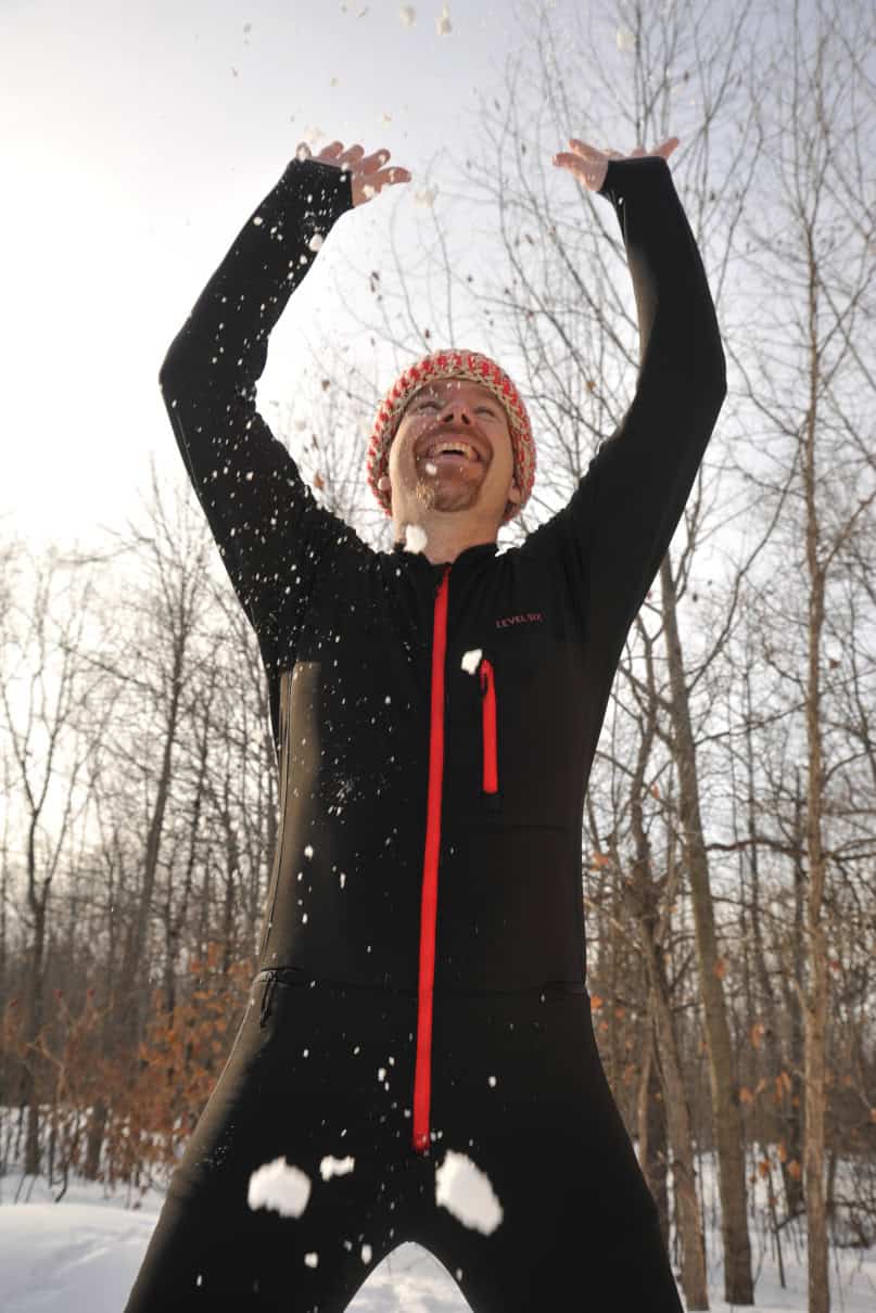 Man tossing snow while wearing one-piece long underwear.