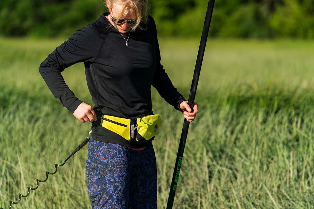 Woman wearing belt pack PFD on paddleboard