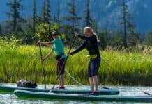 An Inflatable PFD Could Save Your Life: Here’s How To Choose The Right One Two women on paddleboards wearing belt packs.