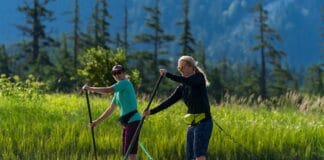 An Inflatable PFD Could Save Your Life: Here’s How To Choose The Right One Two women on paddleboards wearing belt packs.