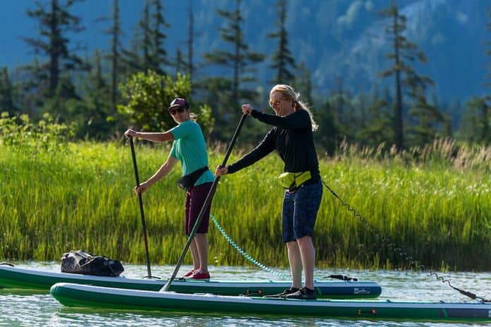 Two women on paddleboards wearing belt packs.