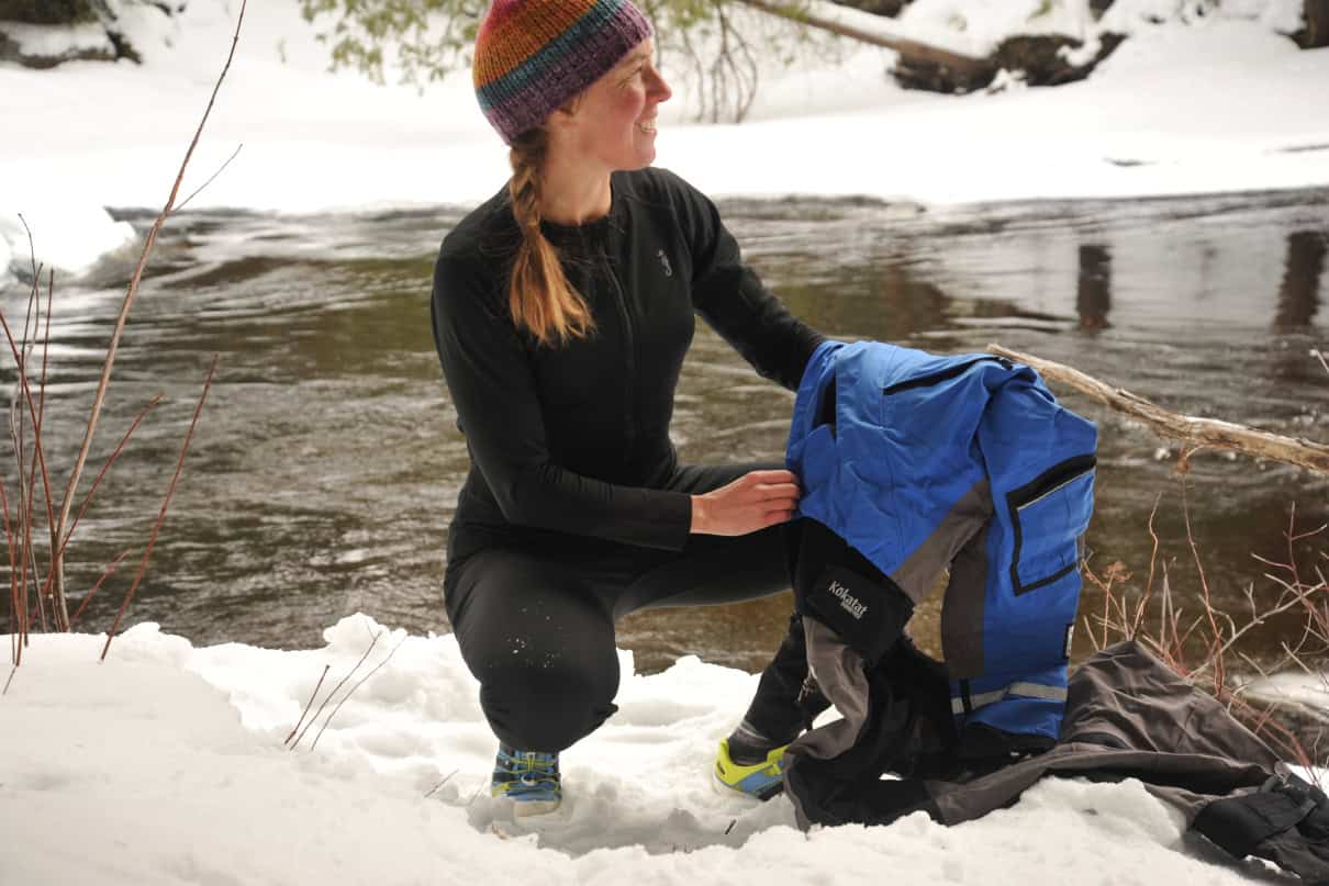 Woman wearing a fleece unionsuit and preparing to put on drysuit.