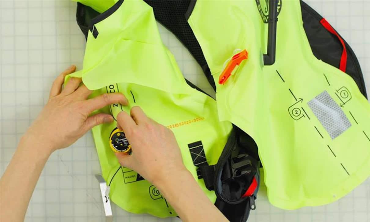 Hands working on rearming an inflatable PFD