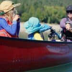 The Next Adventure Mom and two kids paddling in red canoe