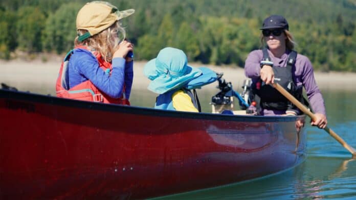 Mom and two kids paddling in red canoe