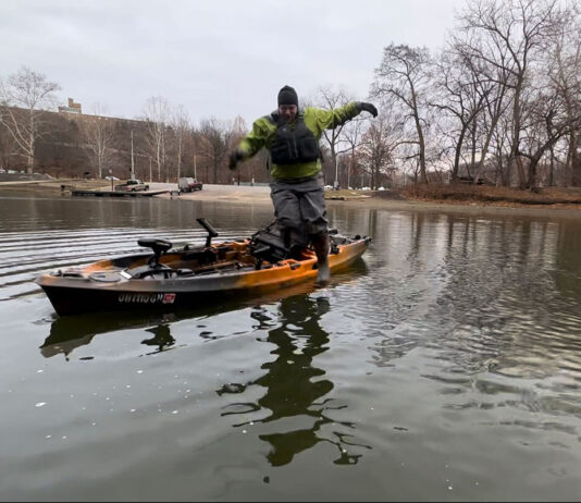 Beginners Guide To Kayak Fishing: Skills & Safety Kayak angler in a drysuit during cold weather tries jumping off his kayak into the water