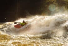 Growing Paddlesports: The Truth Behind The “Butt In Boats” Theory person whitewater kayaking through large rapids in golden light
