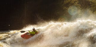Growing Paddlesports: The Truth Behind The “Butt In Boats” Theory person whitewater kayaking through large rapids in golden light
