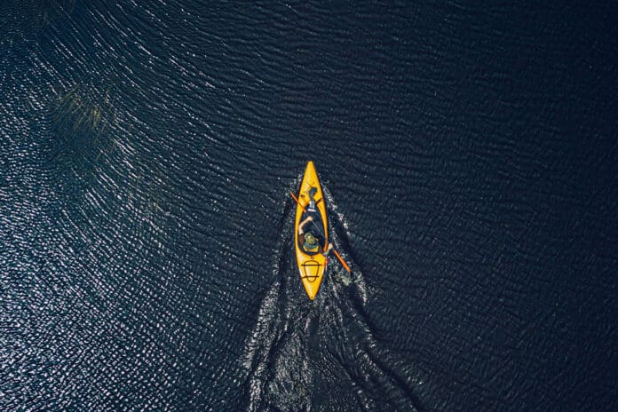 overhead shot of yellow kayak paddled on blue water