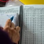 How To Read A Tide Table a person makes handwritten notes while scanning through a spiral bound tide table